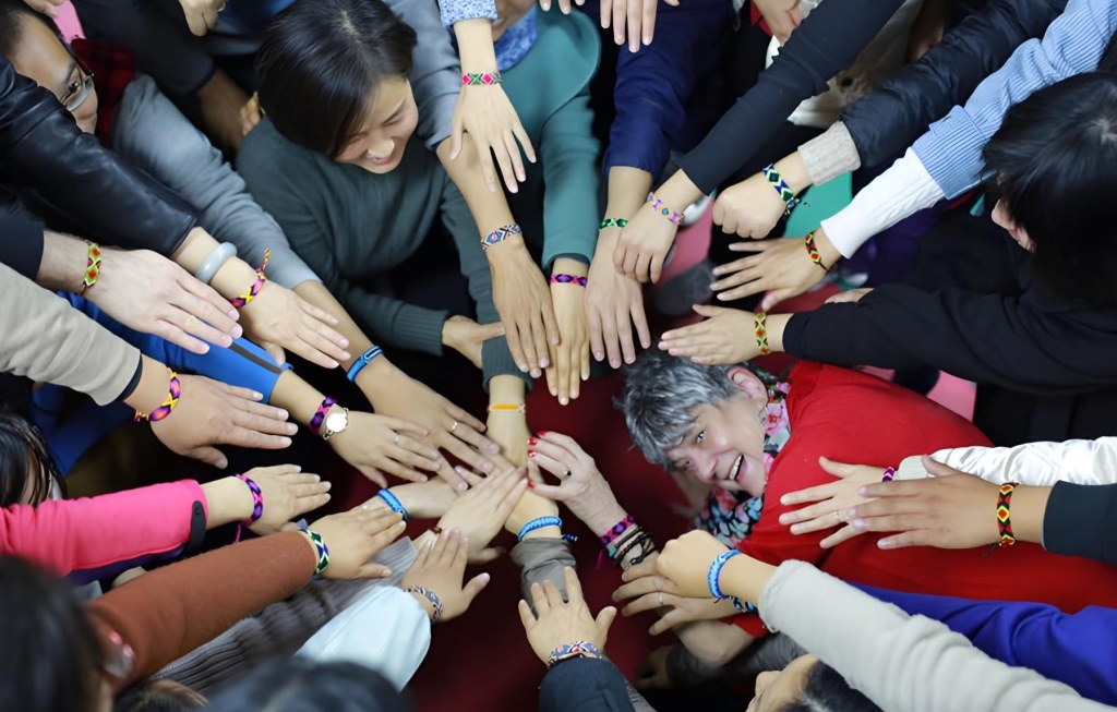 Mary under Participant’s Hands Showing Off Bracelets Received After ATD Symposium