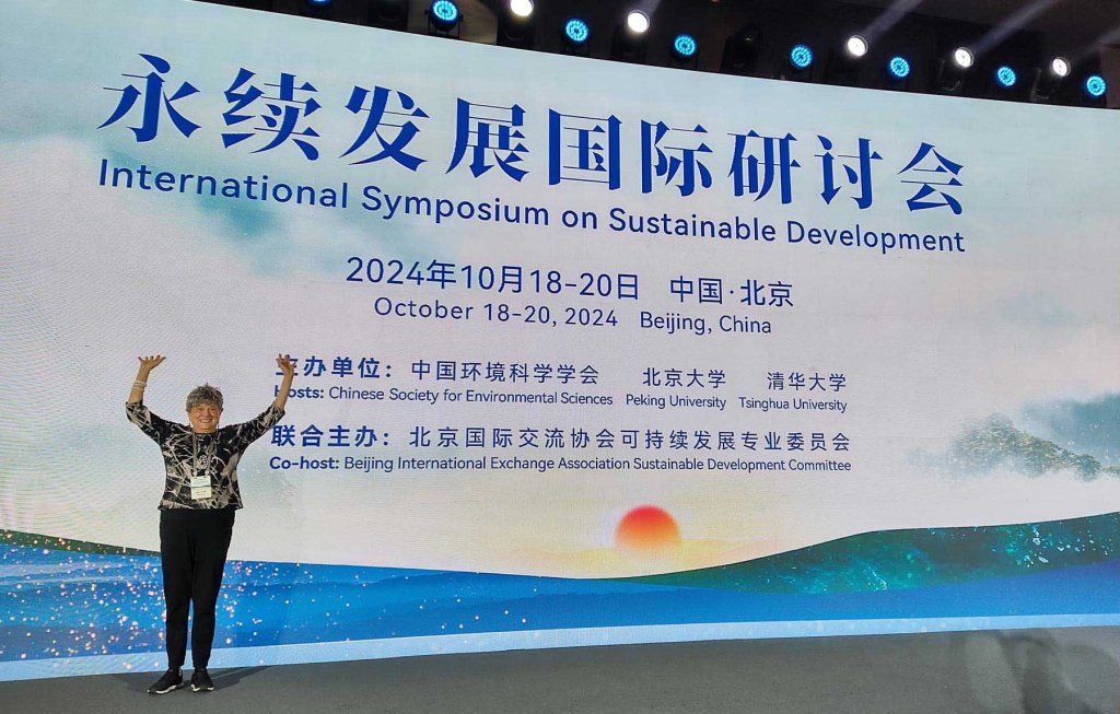 Mary with the Pachamama Alliance Awakening the Dreamer Symposium banner behind her